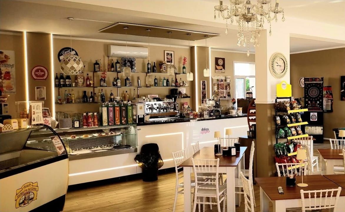 Il bancone bar di Dolce Amaro con la macchina del caffè, le bottiglie sugli scaffali illuminati e la vetrina dei gelati